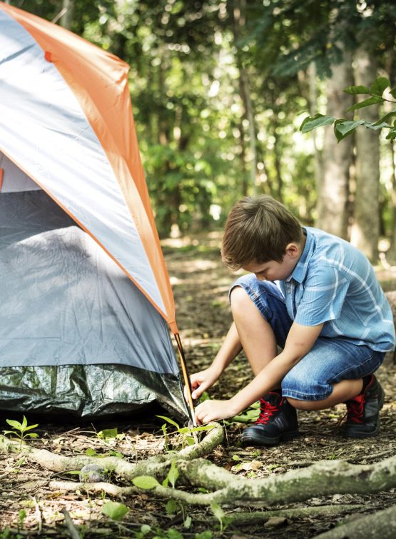 A boy putting up his tent.